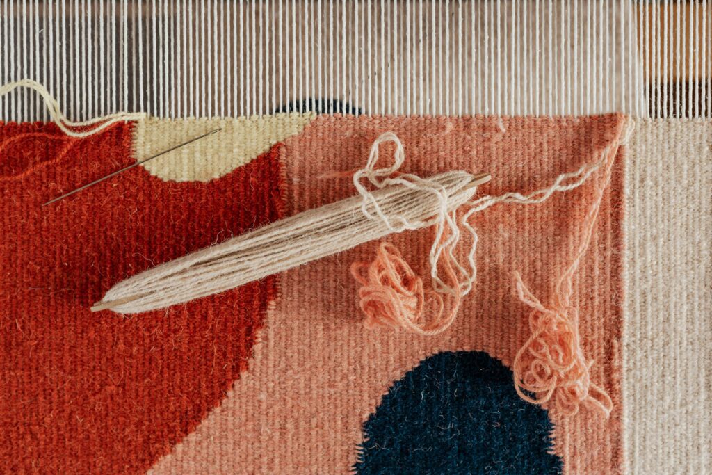 A close up of a rug with yarn and a loom