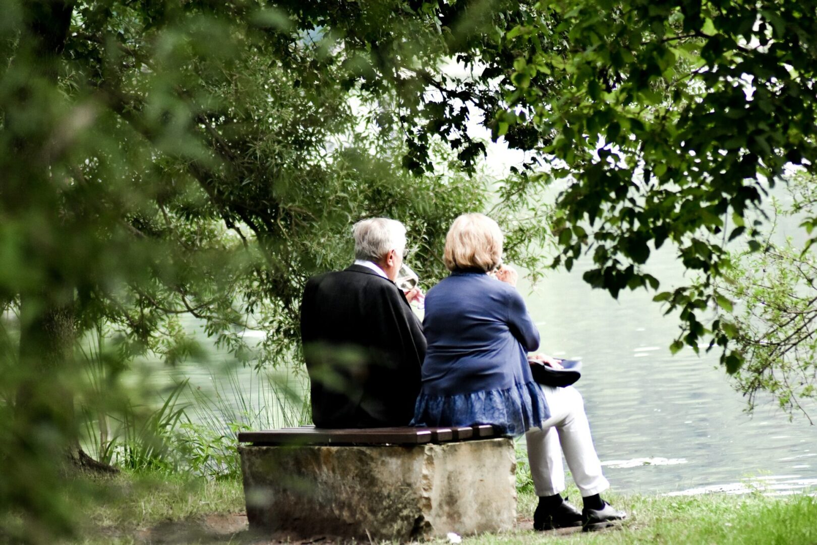 Two people sitting on a bench near the water.